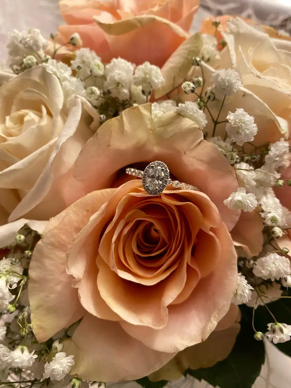 Diamondboi engagement ring resting in a peach rose