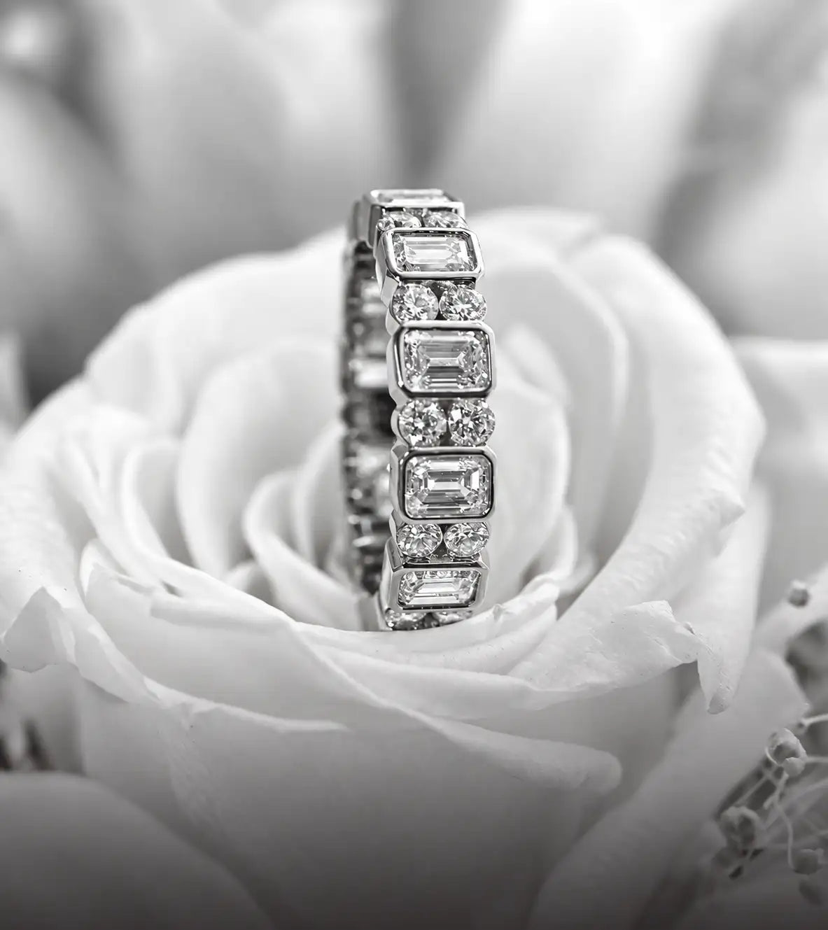 A sparkling diamond eternity band with emerald-cut stones set in a sleek, reflective metal.