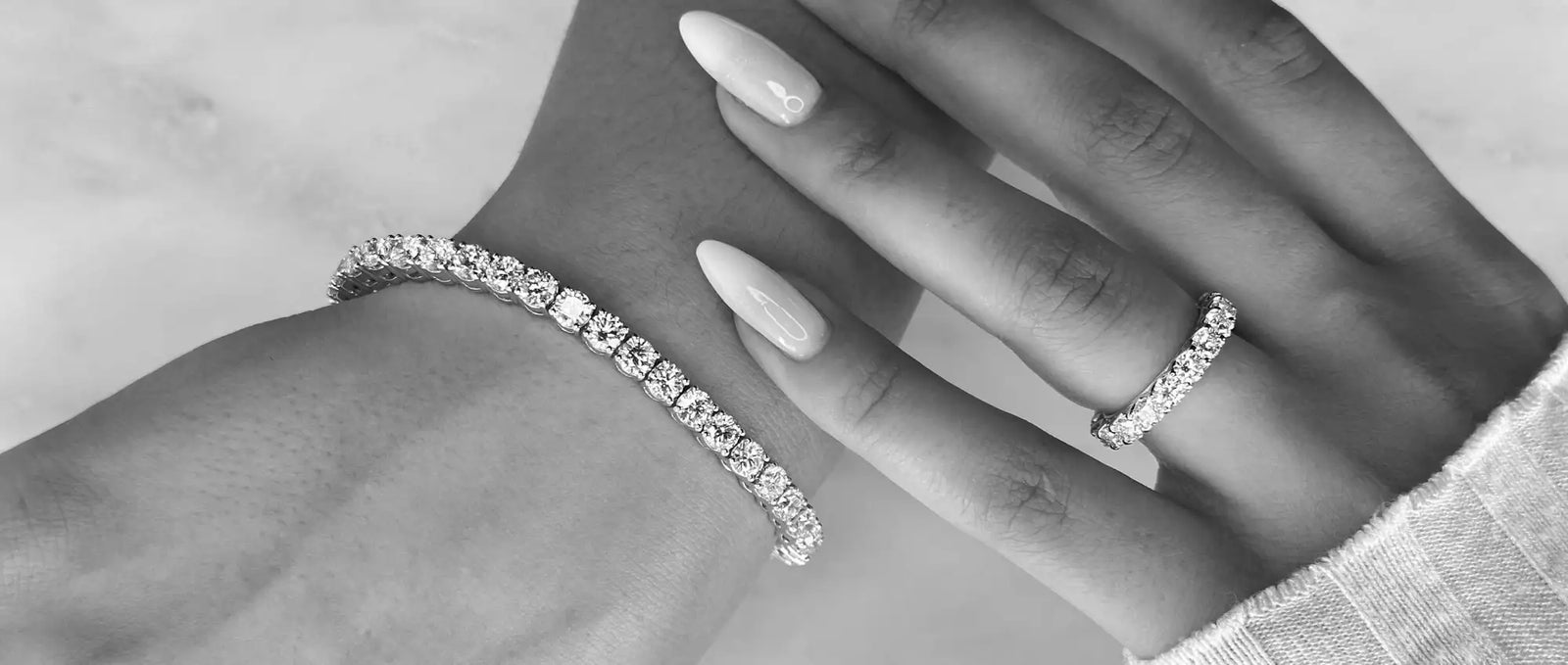 A sparkling diamond tennis bracelet and matching band ring, both featuring a continuous line of brilliant-cut stones set in sleek white metal.