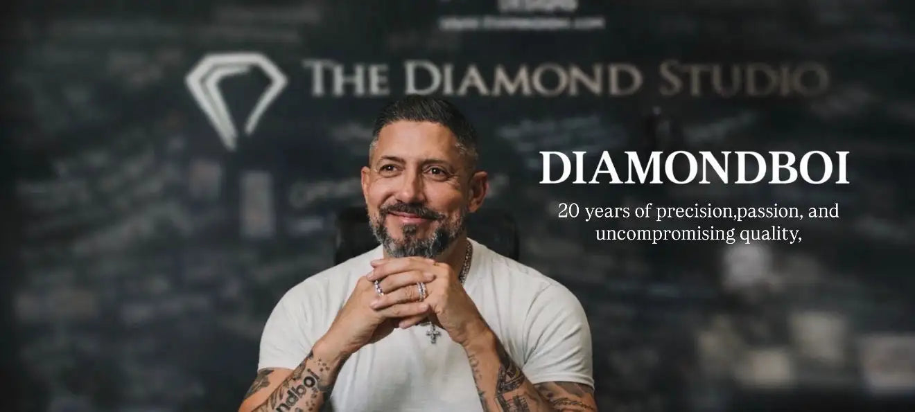 A man with a beard and tattoos wears a white t-shirt, clasping his hands together in front of him.