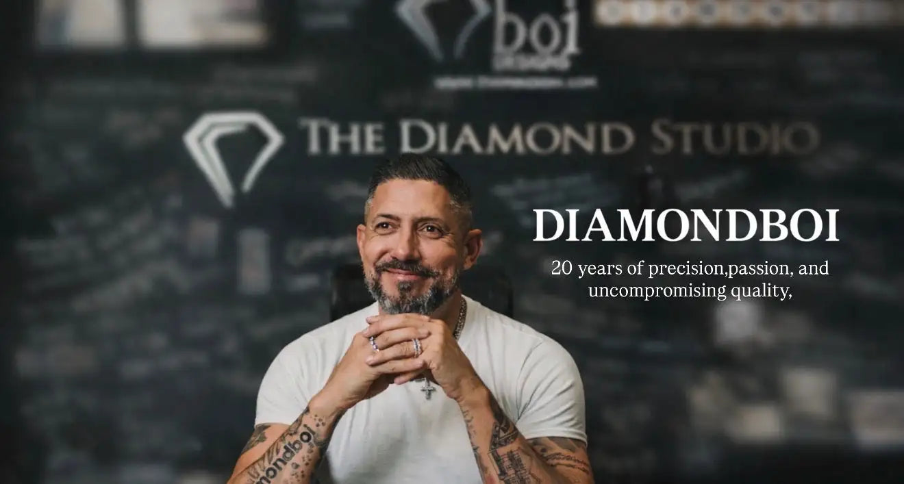 A man with a beard and tattoos wears a white t-shirt while seated in front of a branded backdrop for diamondboi.