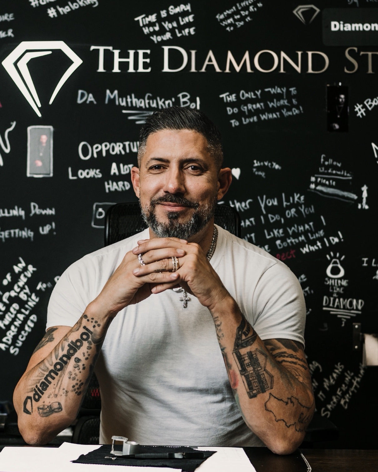 Nuno, founder of diamondboi, seated at his desk in front of the studio's chalkboard wall
